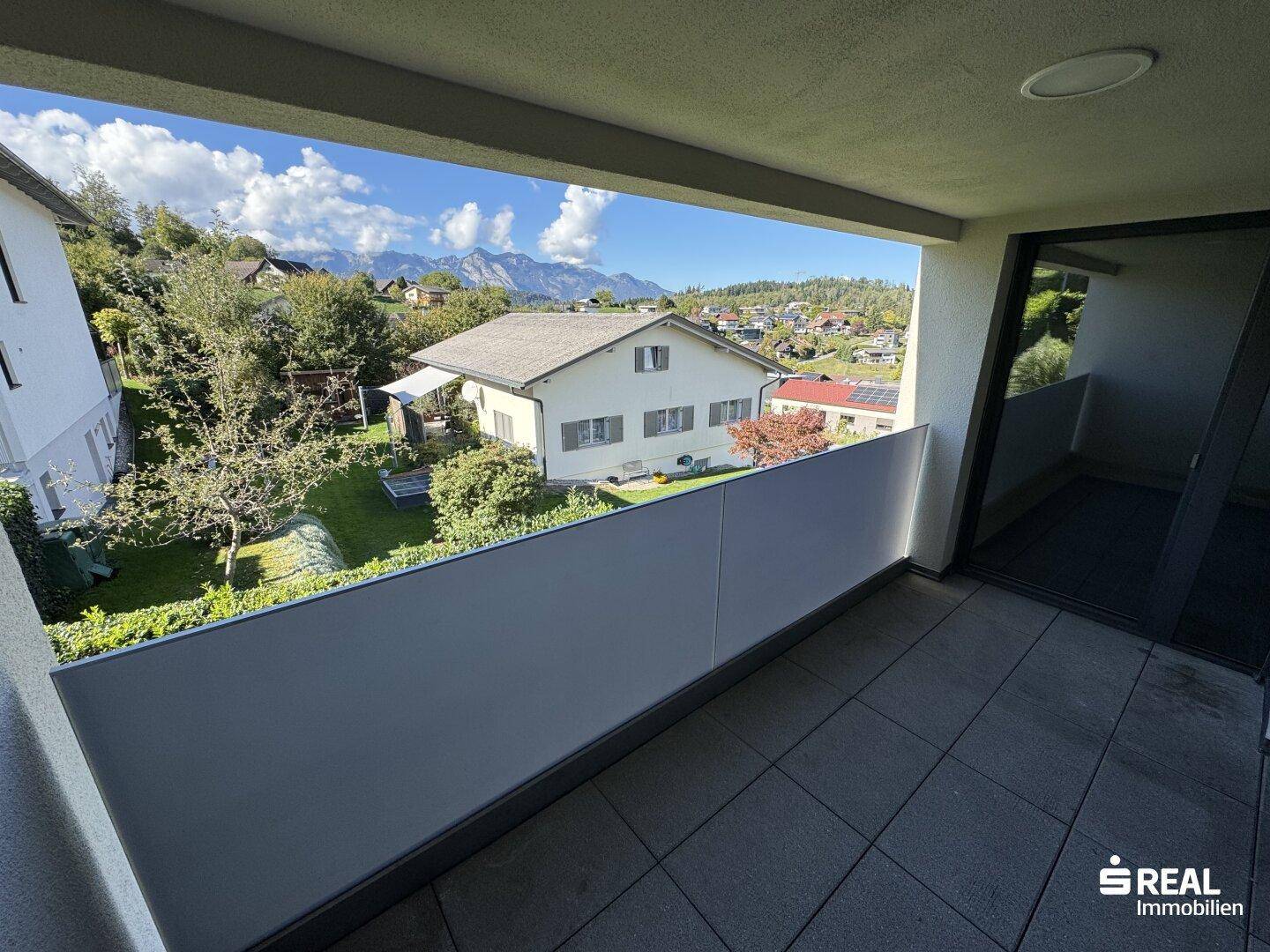 Balkon mit weitem Blick über die umliegende Wohngegend und die beeindruckende Berglandschaft.