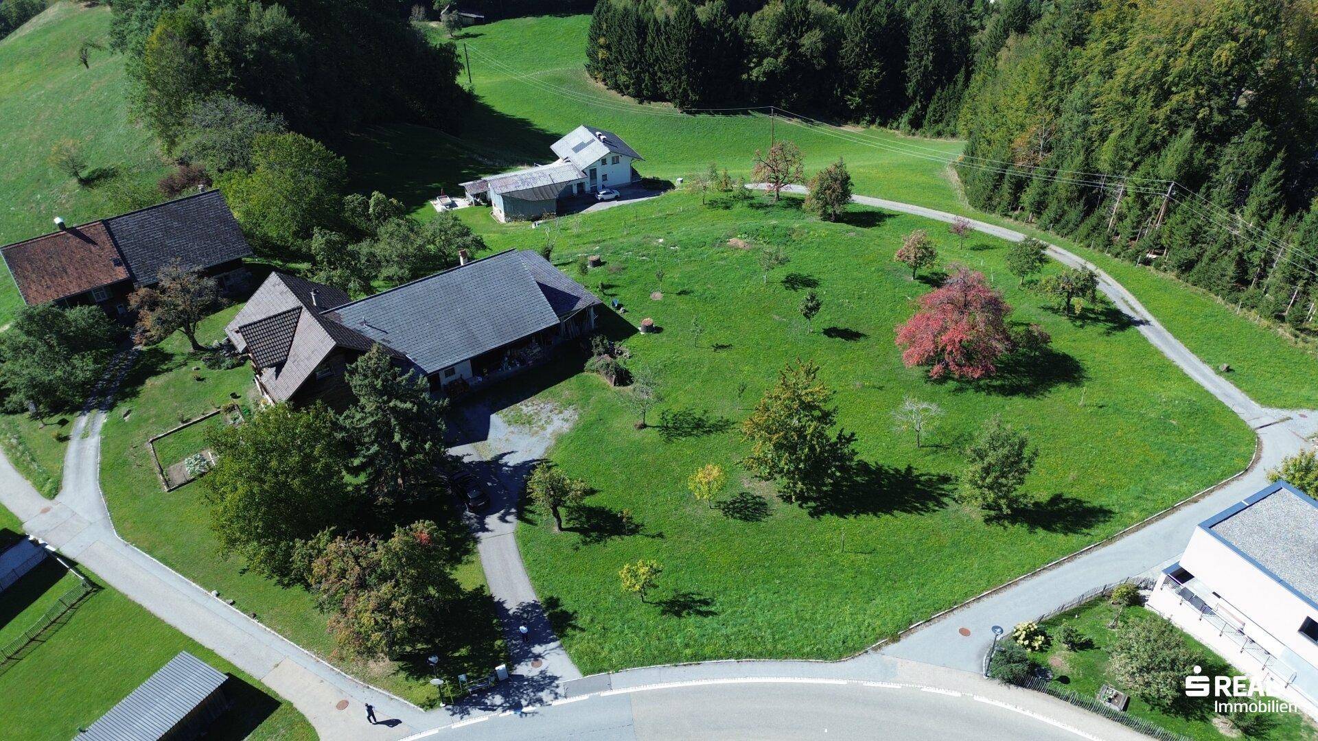 Weitläufiges Grundstück mit einem traditionellen Haus, umgeben von grünen Wiesen und Zufahrtsstraßen.