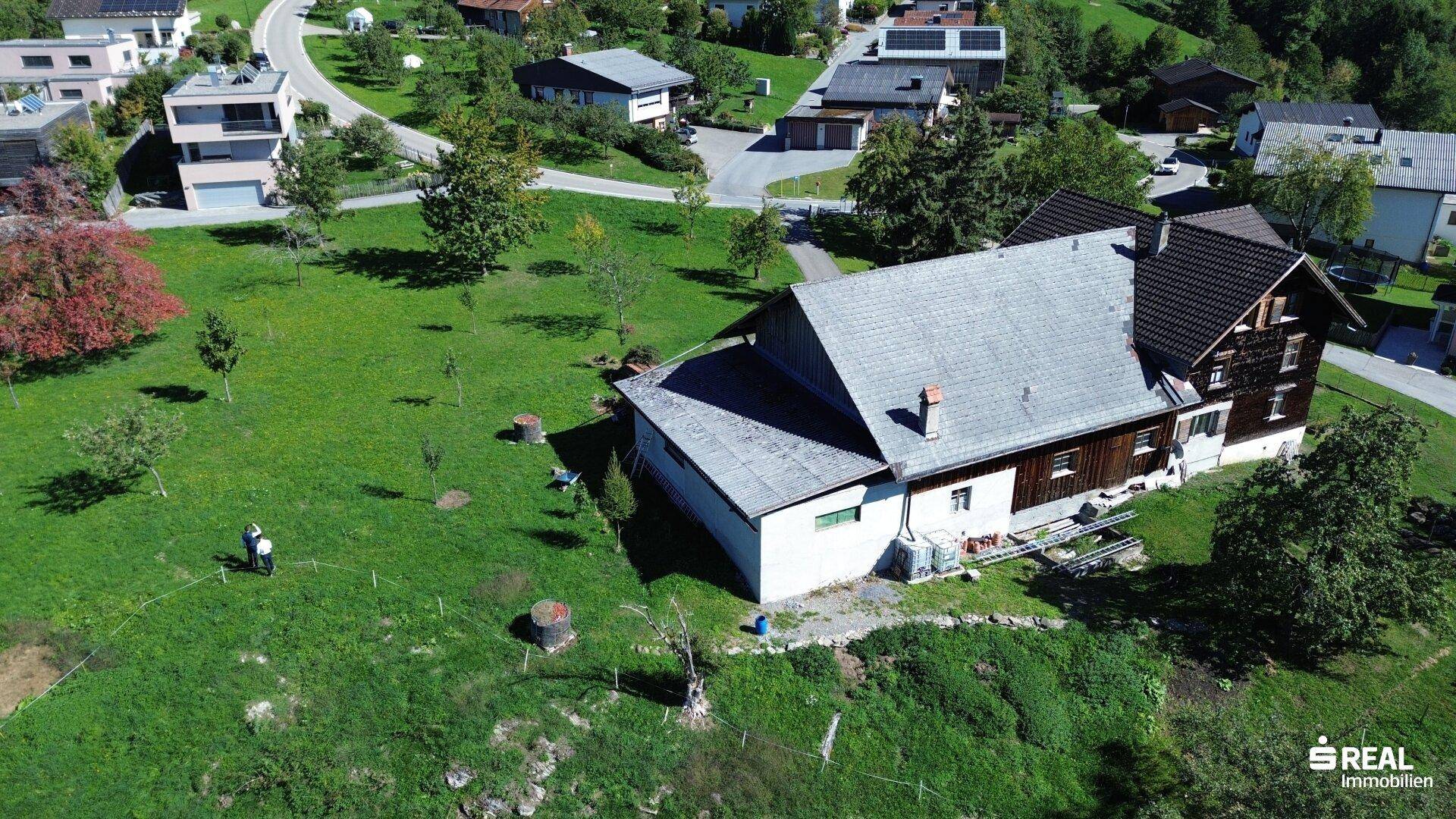 Luftaufnahme des Hauses mit Anbau und weitläufigem Gartenbereich, umgeben von grüner Landschaft.