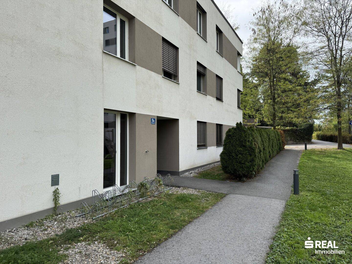 Modernes Mehrfamilienhaus mit gepflegter Fassade und Grünflächen im Außenbereich.