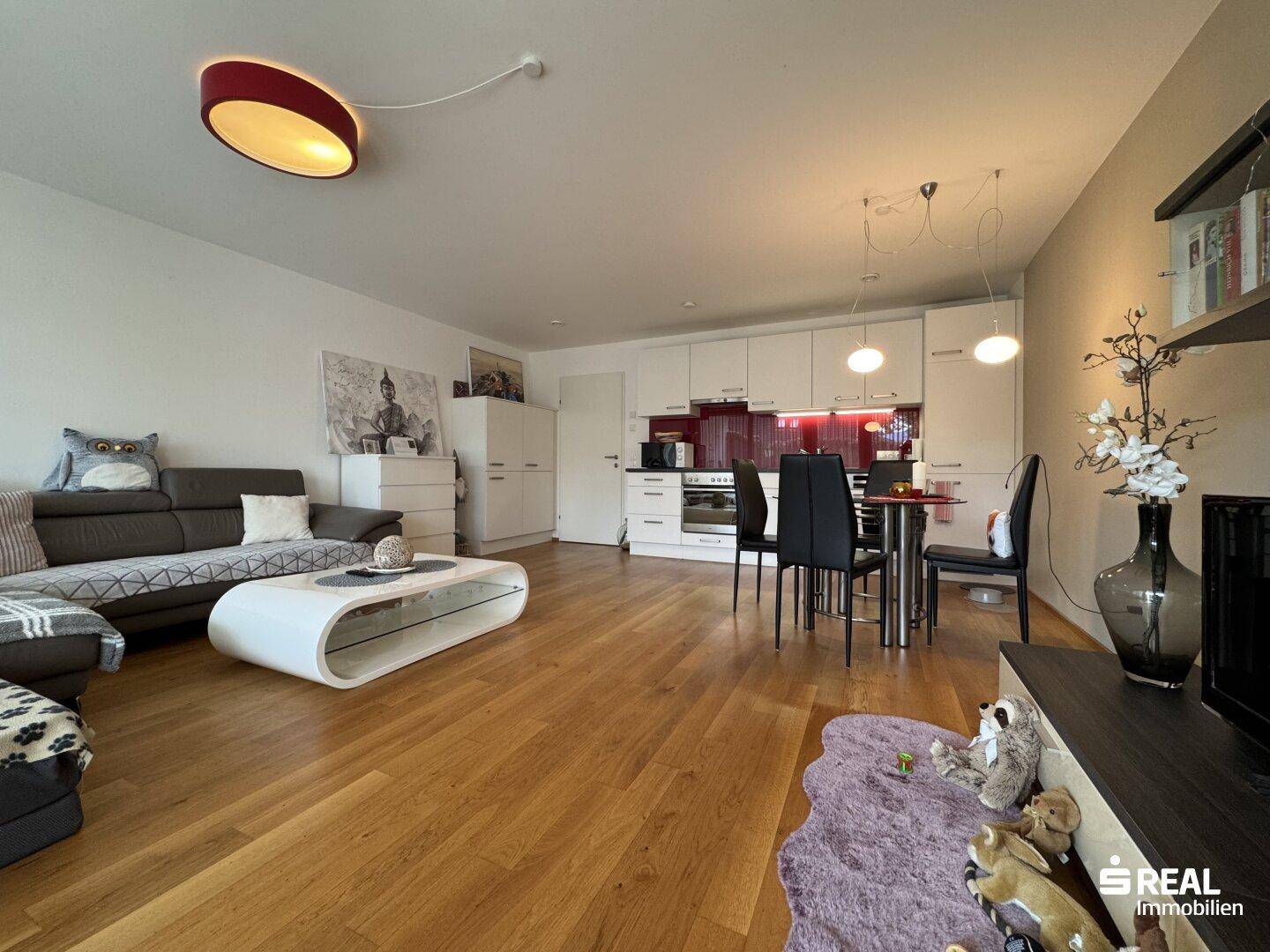 Heller offener Wohn-Essbereich mit integrierter Küche und Holzboden, ideal für modernes Wohnen.