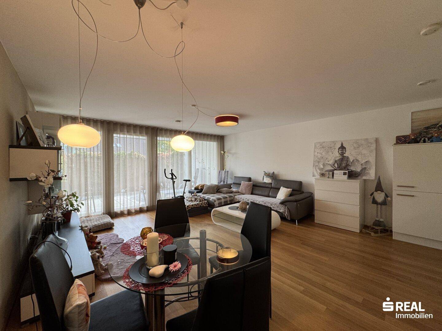 Geräumiger Wohn- und Essbereich mit großen Fenstern und Zugang zu einem Außenbereich.