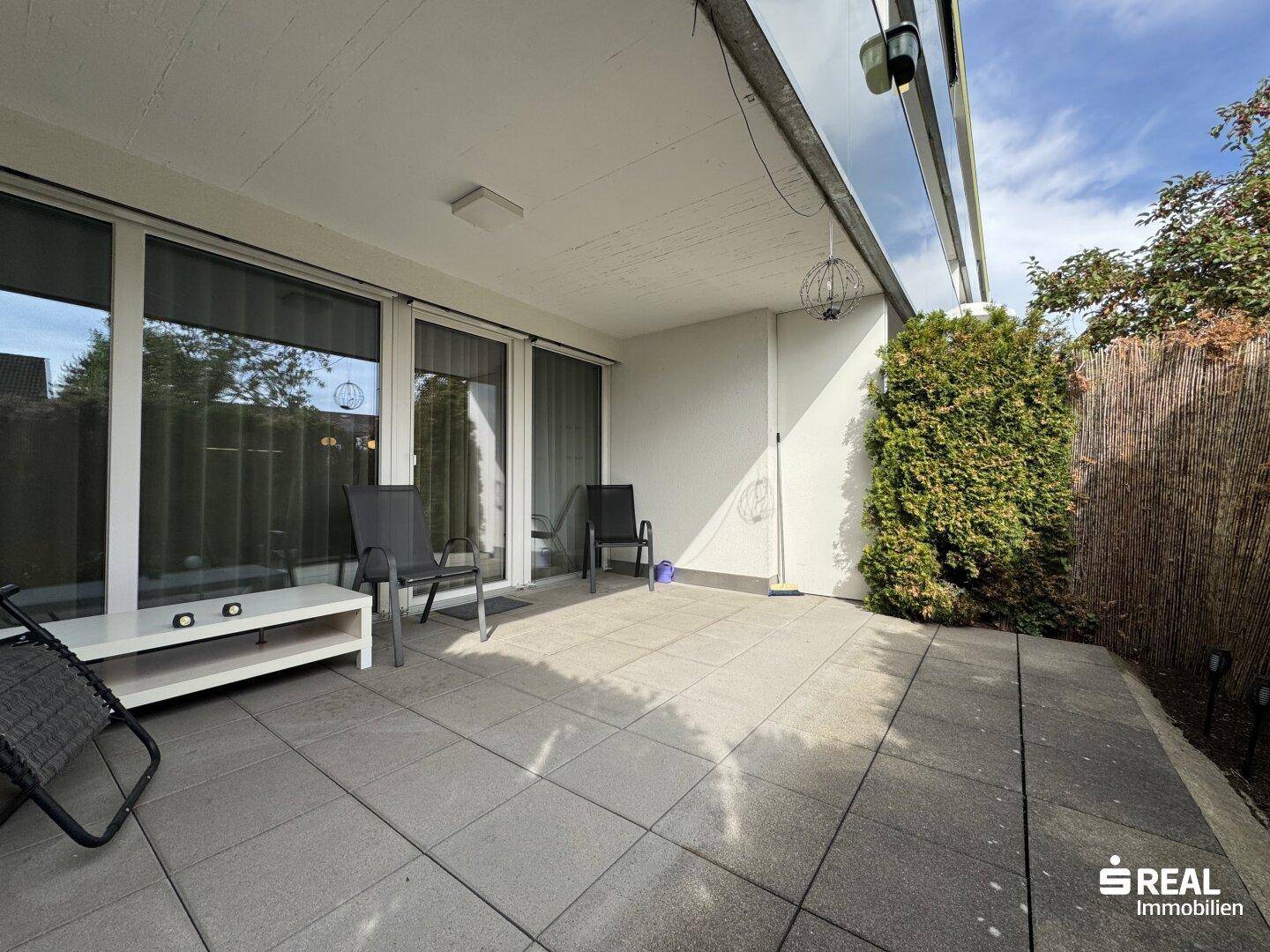 Geräumige Terrasse mit Fliesenboden und Sichtschutz, bietet Privatsphäre und Außenbereich.