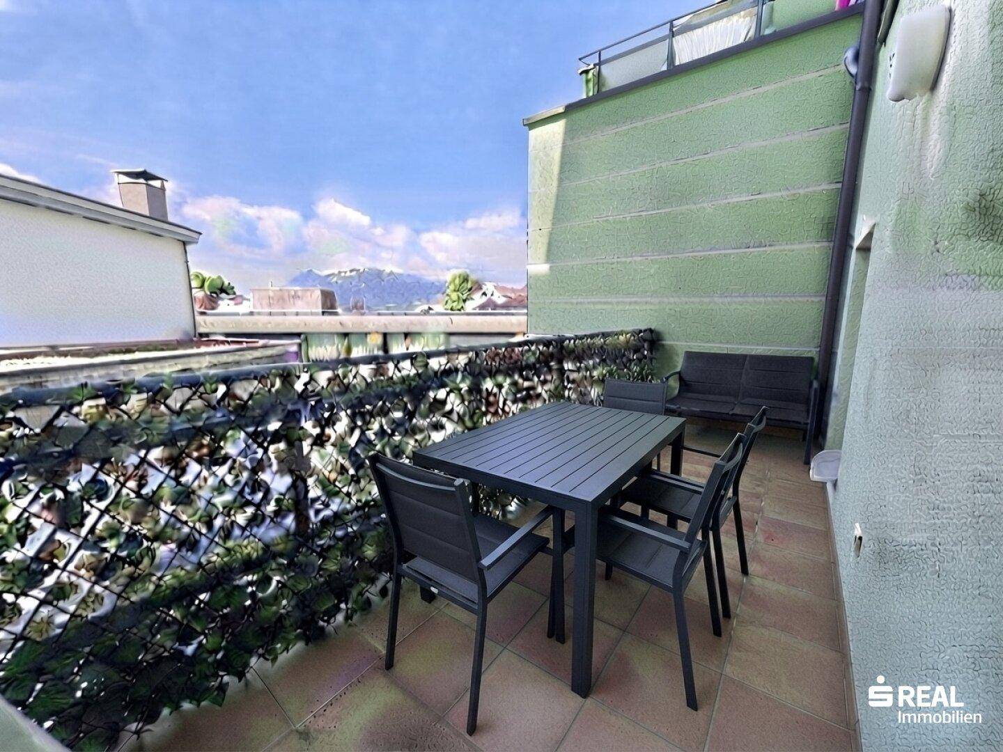 Möblierte Dachterrasse mit Esstisch, Stühlen und Blick auf die Berge.