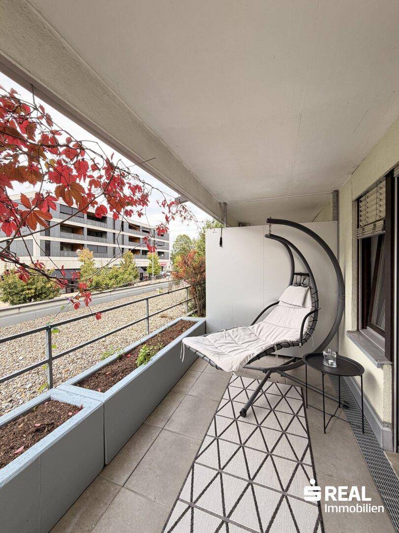 Gemütlicher Balkon mit Hängesessel, Pflanzen und Blick auf die Umgebung.