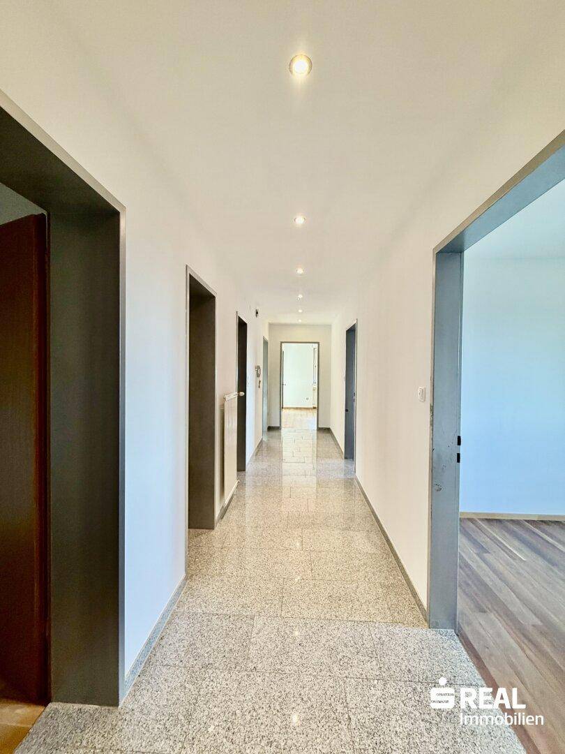 Heller Flur mit Fliesenboden und Zugang zu verschiedenen Zimmern der Wohnung.