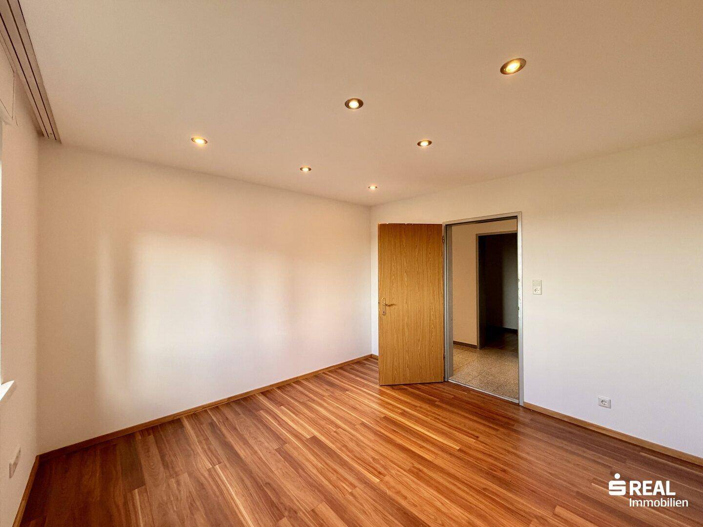 Geräumiges Zimmer mit Holzboden und Einbaustrahlern, ideal als Schlaf- oder Arbeitszimmer.