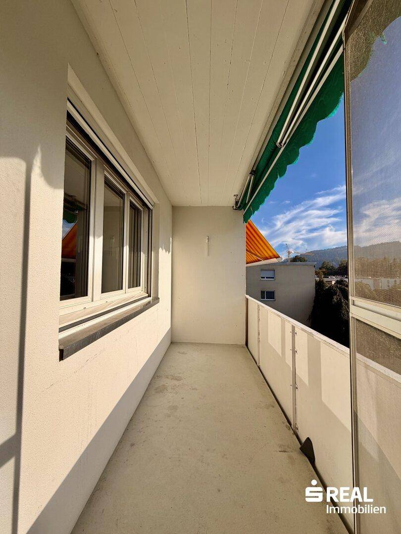 Langer, schmaler Balkon mit Markise und Blick auf die umliegende Bebauung.