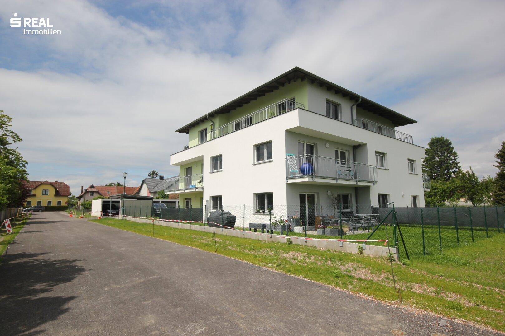 Modernes Wohngebäude mit Balkonen und Terrassen, umgeben von einer gepflegten Grünfläche.