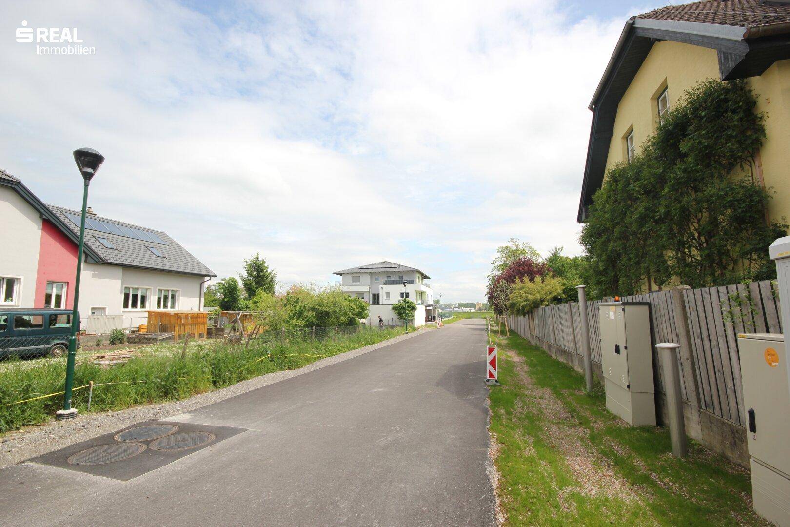 Ländliche Wohngegend mit Einfamilienhäusern und viel Grün entlang der Straße.