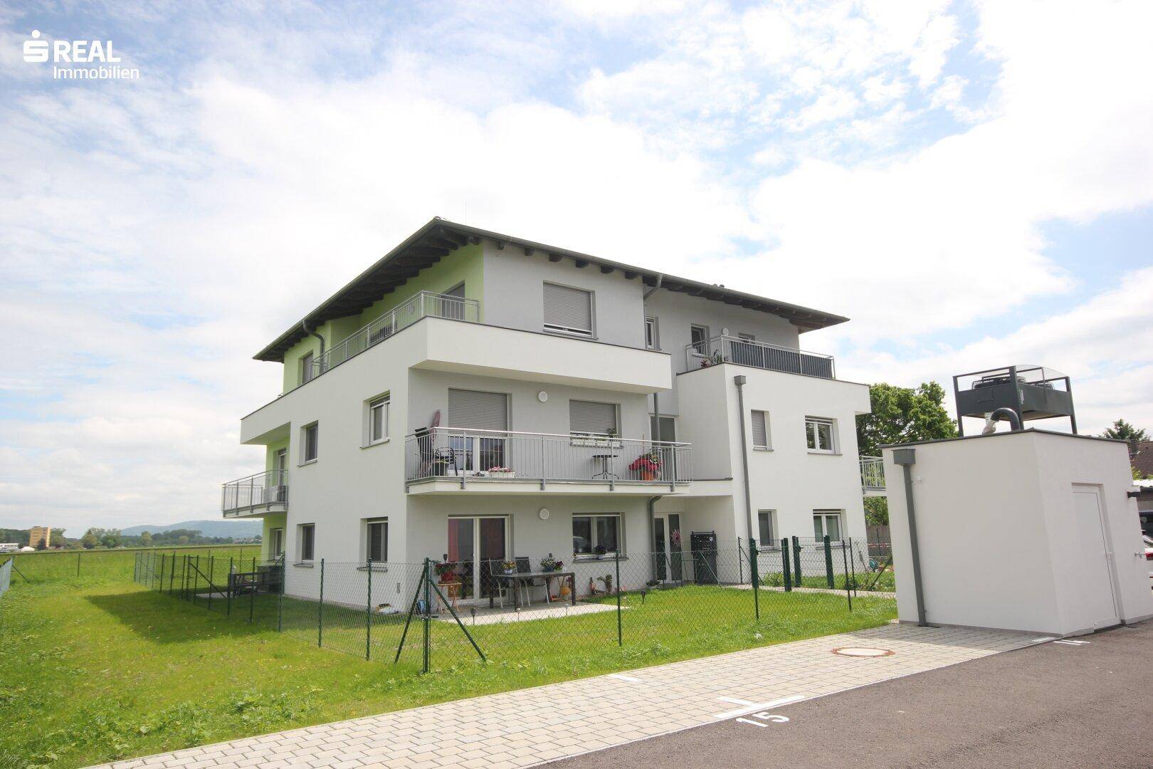 Modernes Mehrfamilienhaus mit hellen Fassadenfarben und Zugang zu Balkonen und Terrassen.