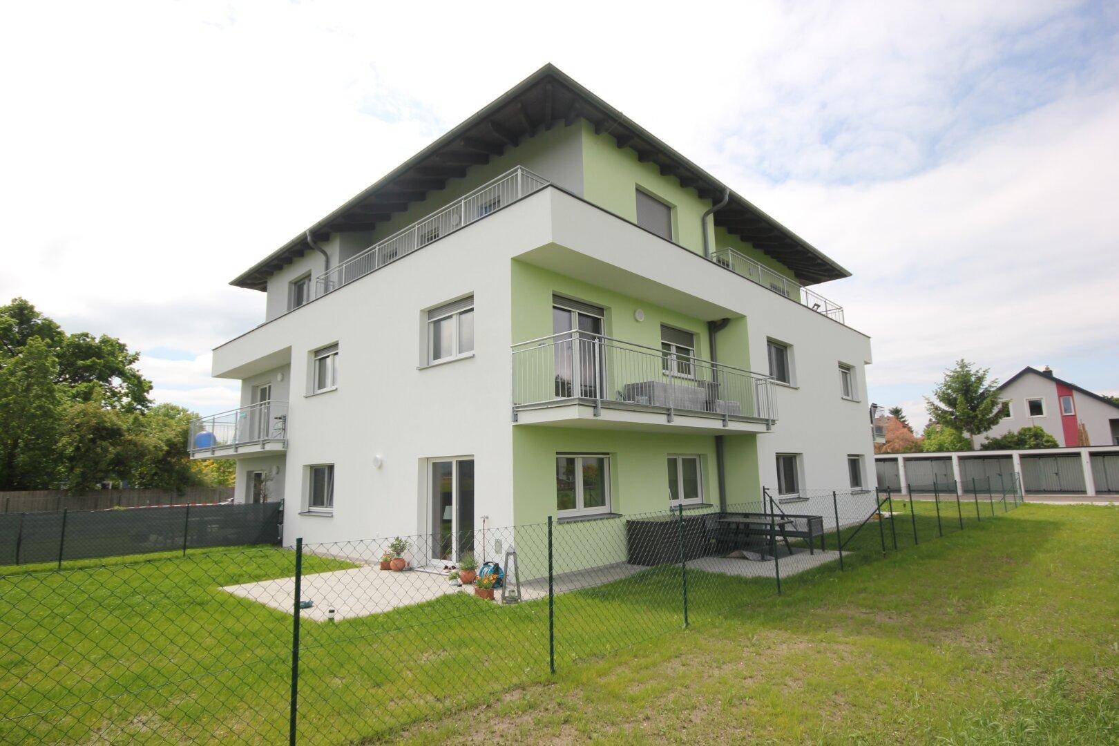Modernes Wohngebäude mit privater Terrasse und Gartenbereich im Erdgeschoss.