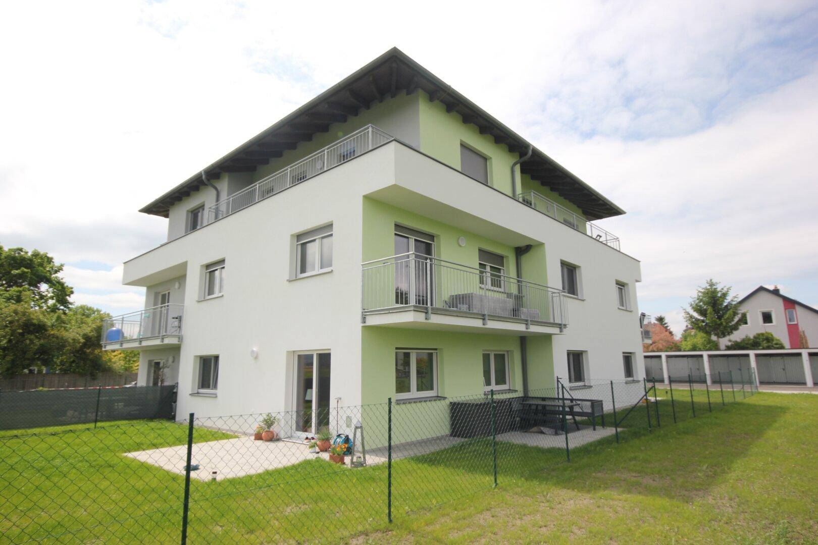 Ansicht des Neubaus mit zugänglichem Gartenbereich und kleiner Terrasse.