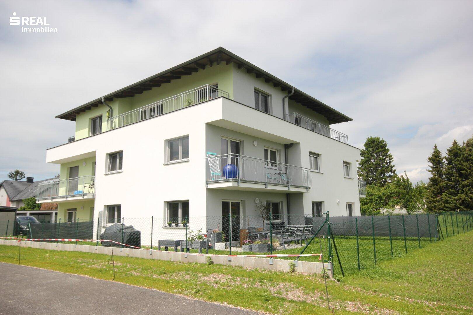Ansicht des modernen Wohngebäudes mit Balkonen und Terrassen in einer grünen Umgebung.