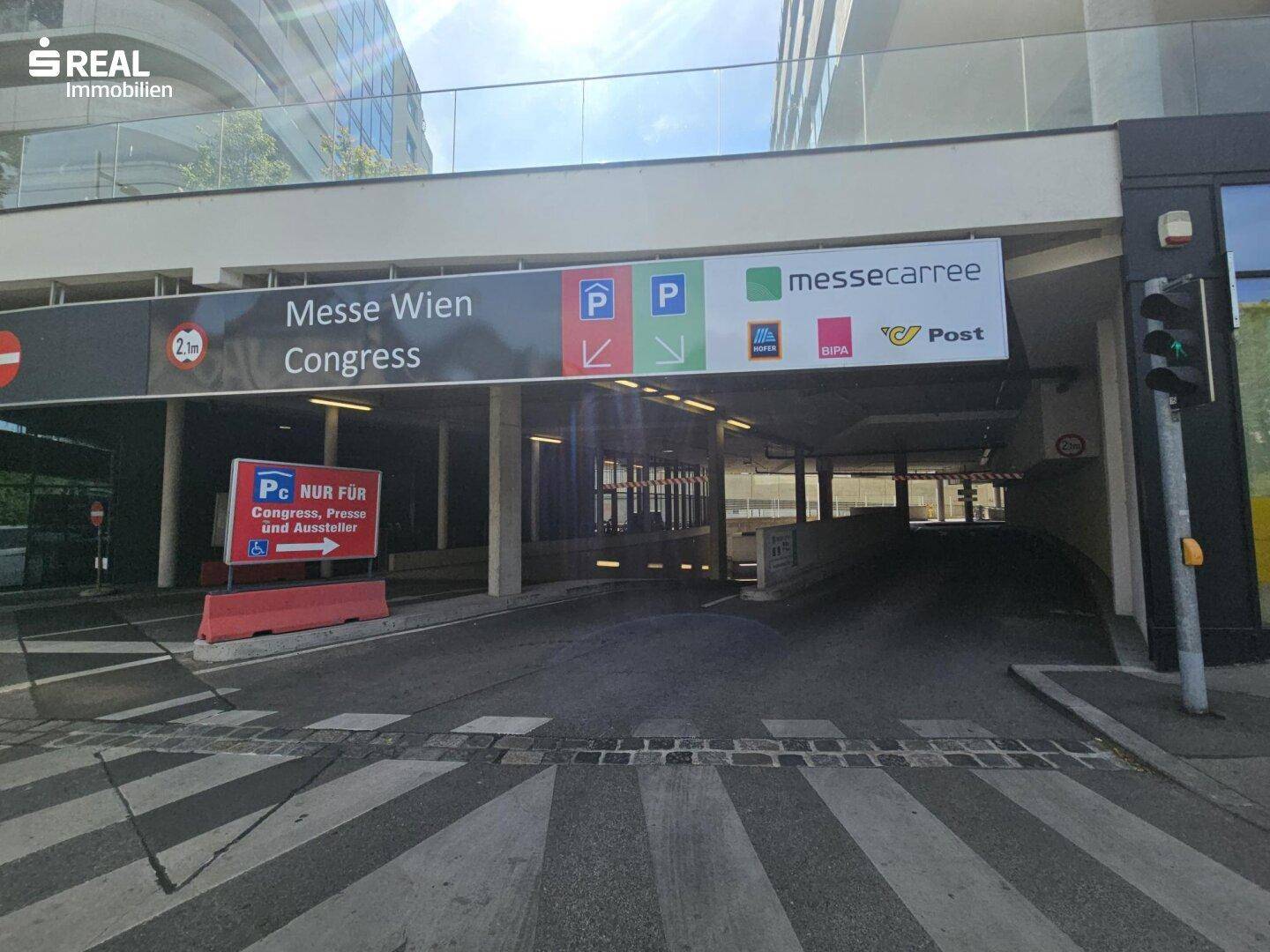 Zufahrt zur Tiefgarage mit Hinweisschildern für die Messe Wien und umliegende Geschäfte.