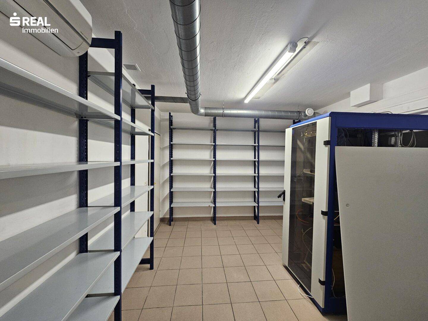 Serverraum mit Regalen, Klimaanlage und sichtbaren Lüftungsrohren.