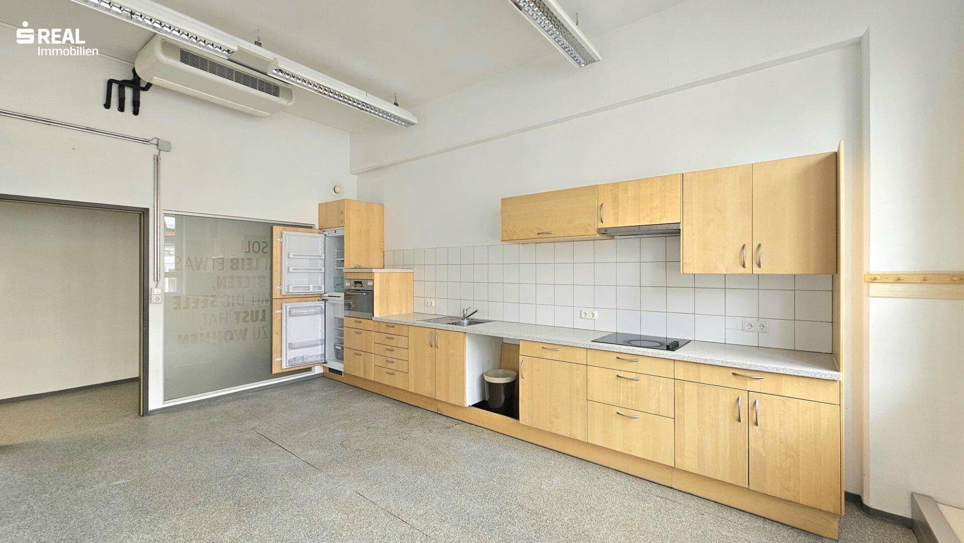 Funktionale Einbauküche mit Holzschränken, Fliesenrückwand und integrierten Geräten.