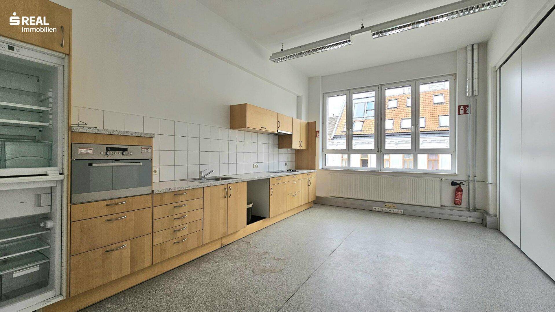 Geräumige Küche mit Holzschränken, Fliesenrückwand und großen Fenstern für viel Licht.