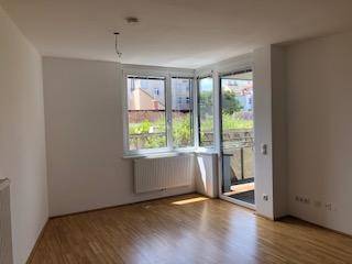 Lichtdurchfluteter Raum mit Eckfenster, Heizkörper und Zugang zu einem Außenbereich.