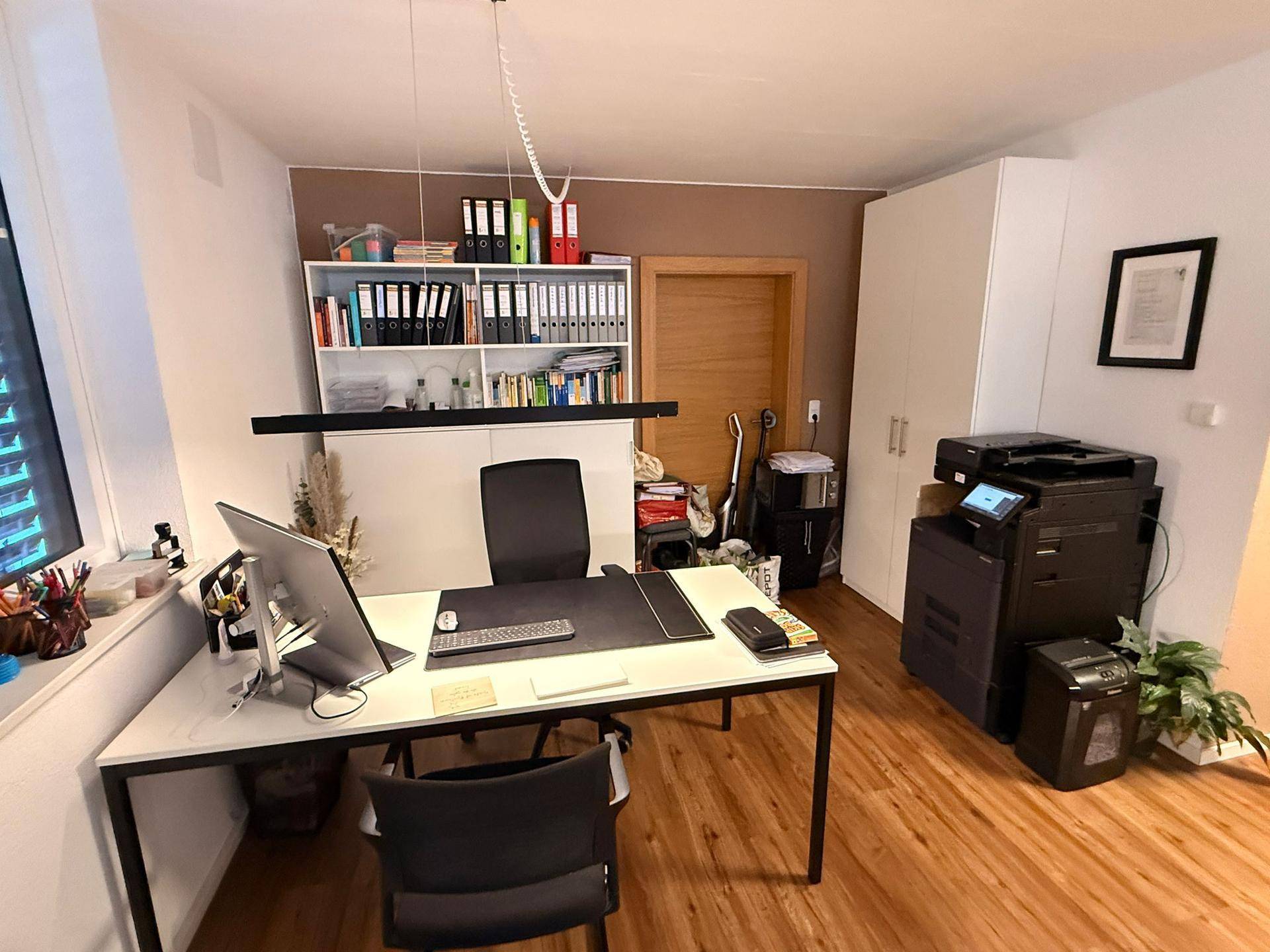 Detailansicht des Büros mit modernem Schreibtisch, Computer und gut organisierten Regalen.