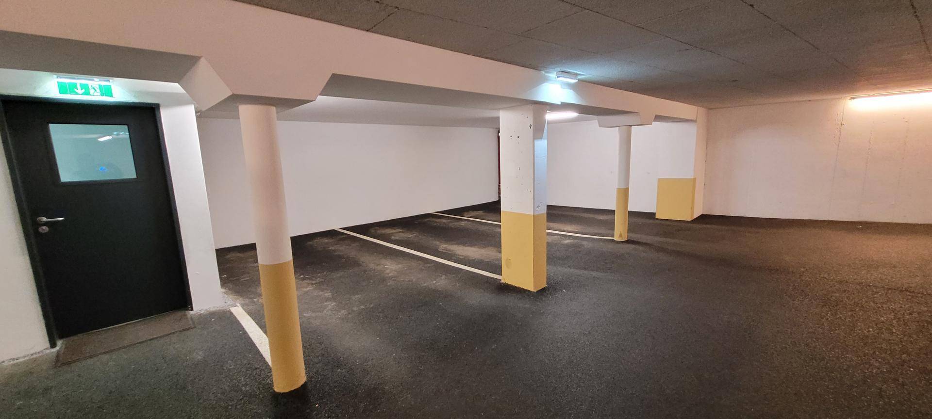 Geräumige Tiefgarage mit markierten Parkplätzen und Säulen.