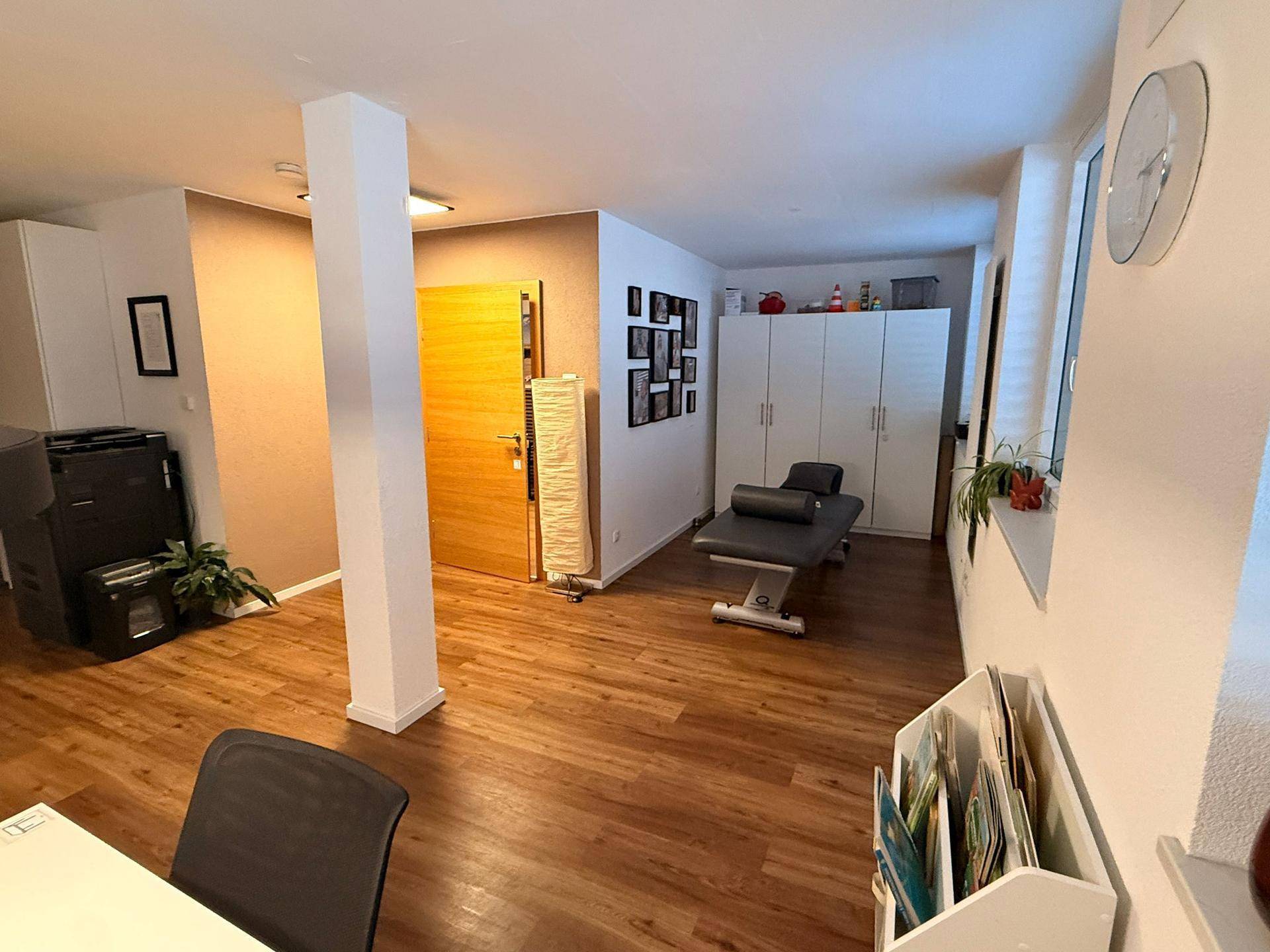 Geräumiger Raum mit Holzboden, Säule und verschiedenen Möbeln, bietet flexible Nutzungsmöglichkeiten.