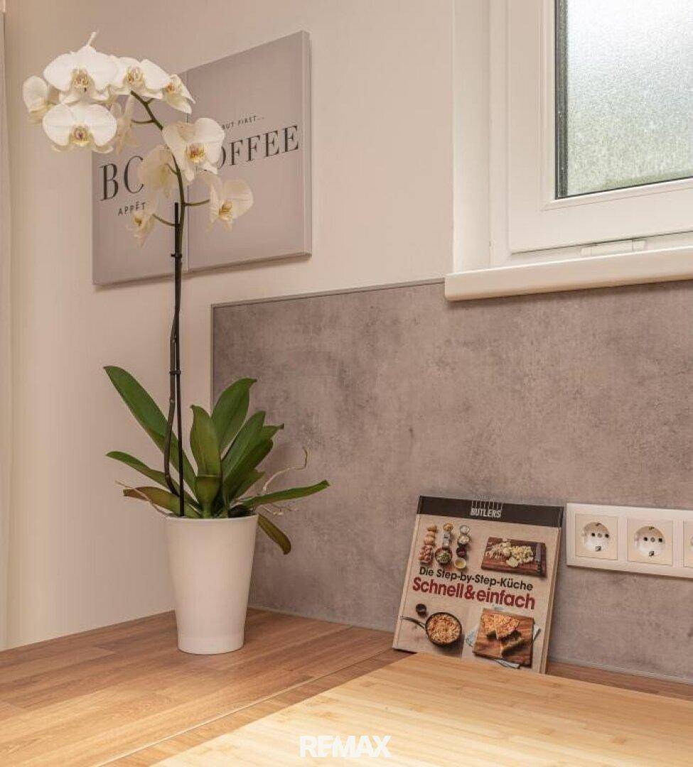 Detailansicht der Küchenarbeitsplatte mit Orchidee, Kochbuch und Steckdosen.