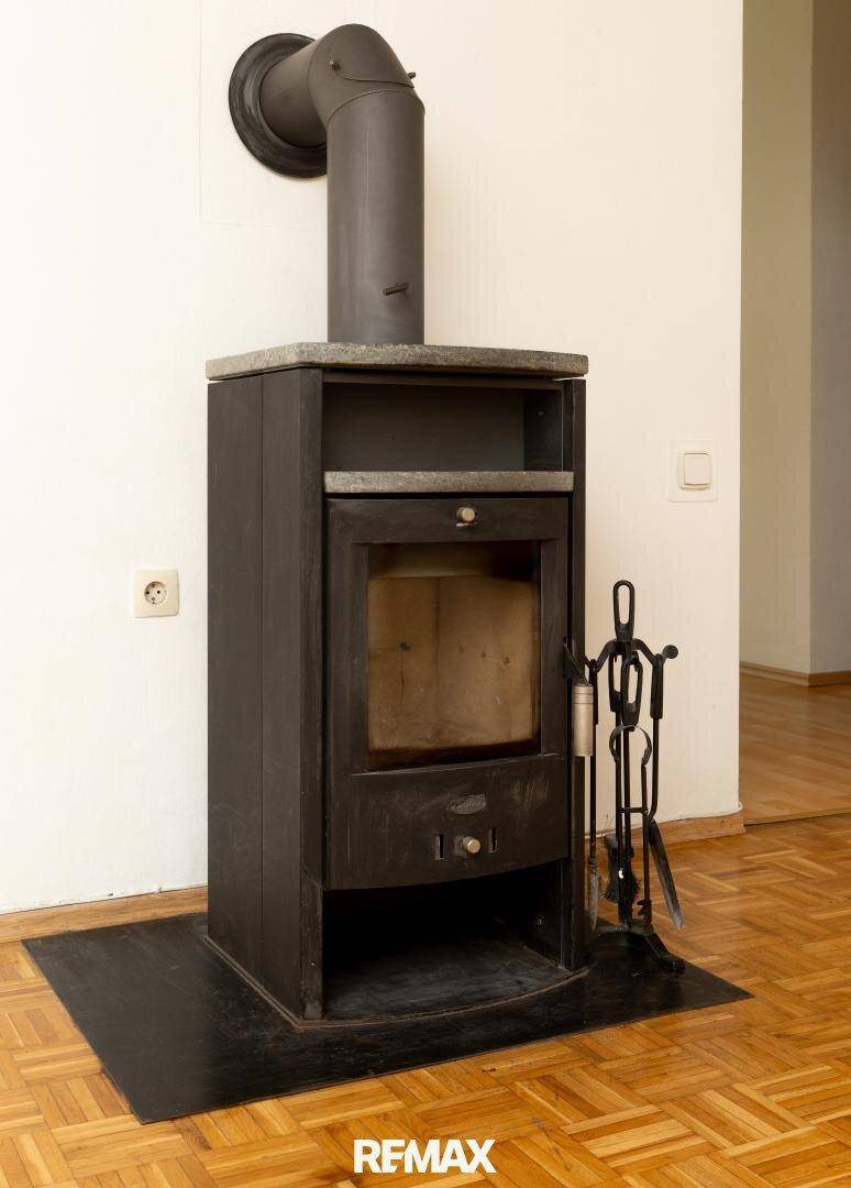 Detailaufnahme eines modernen Kaminofens mit Holzablage im Wohnbereich.