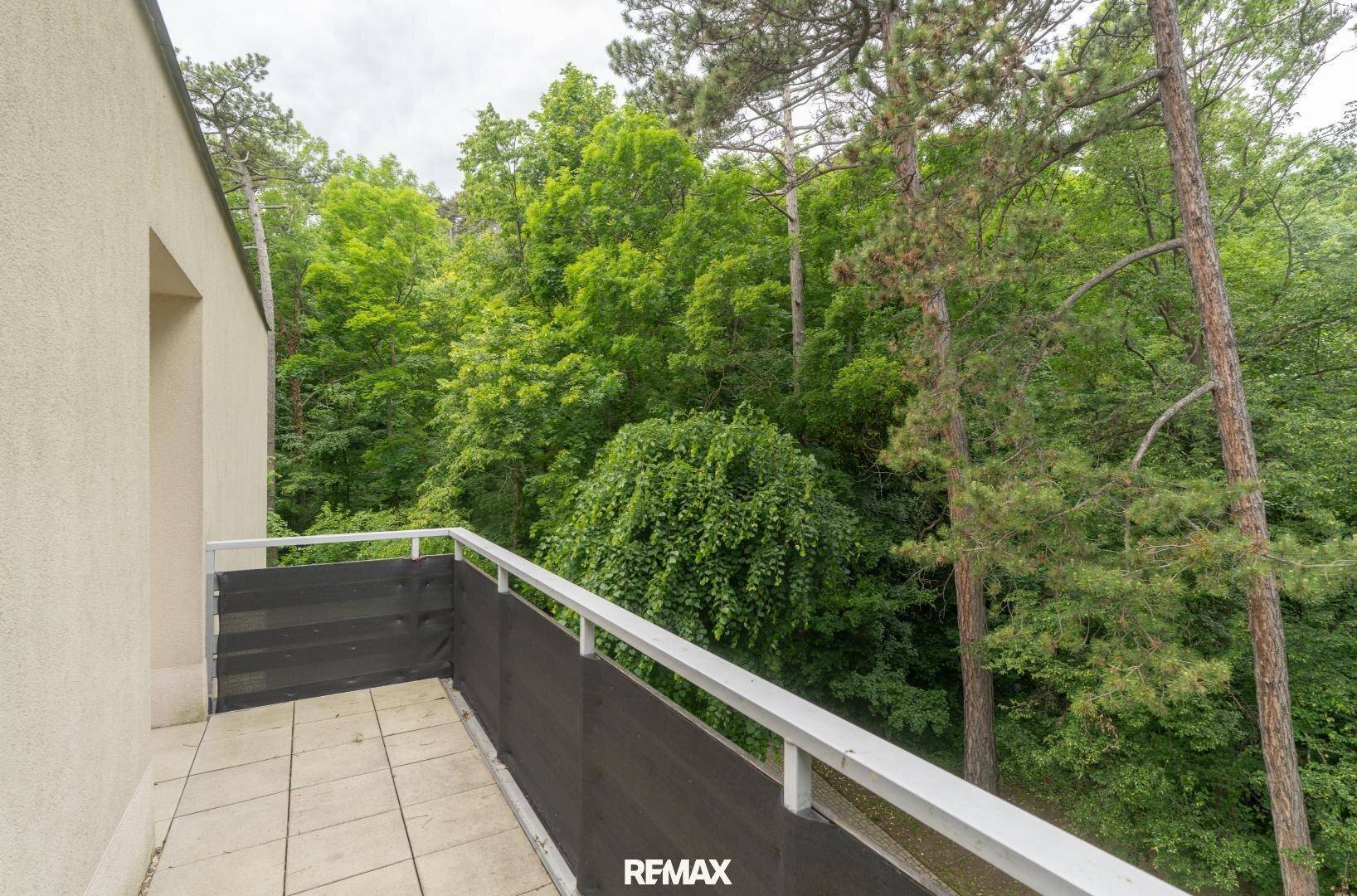 Geräumiger Balkon mit Fliesenboden und weitem Blick ins Grüne.