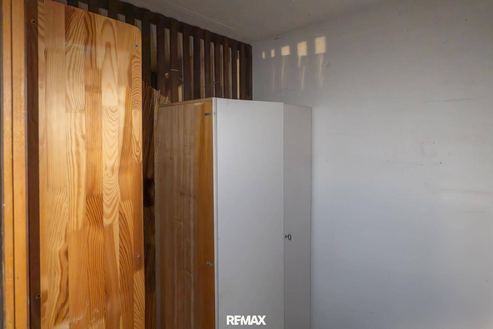 Abstellraum mit Holzverkleidung und einem weißen Schrank, ideal für Lagerung.