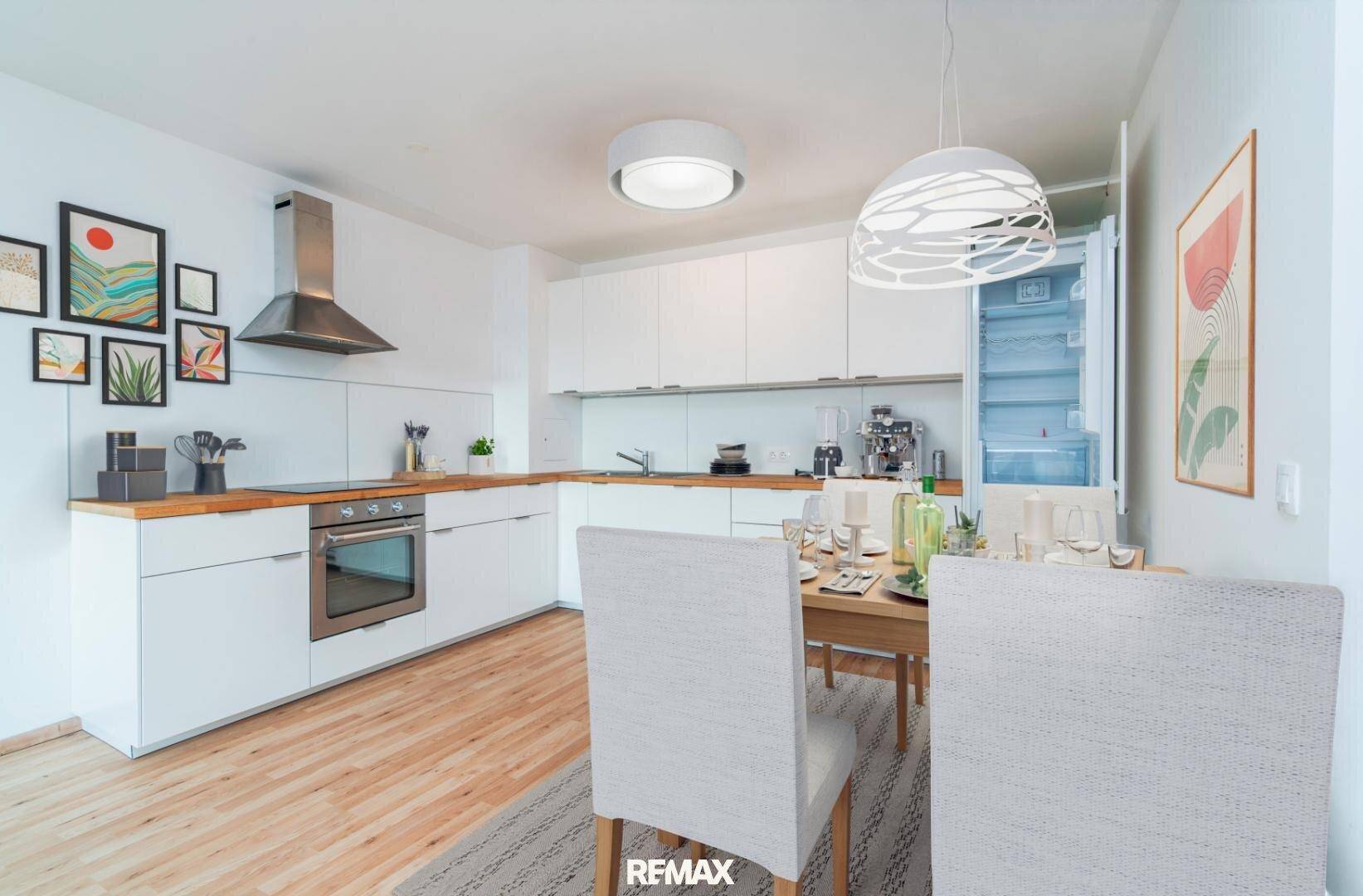 Moderne Küche mit Essbereich, weißen Schränken, Holzarbeitsplatte und integriertem Kühlschrank.