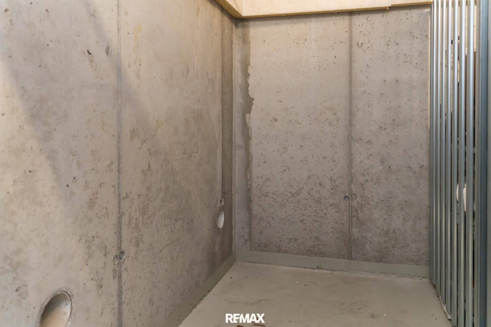 Kellerabteil mit Betonwänden und Metallregalen zur Lagerung.