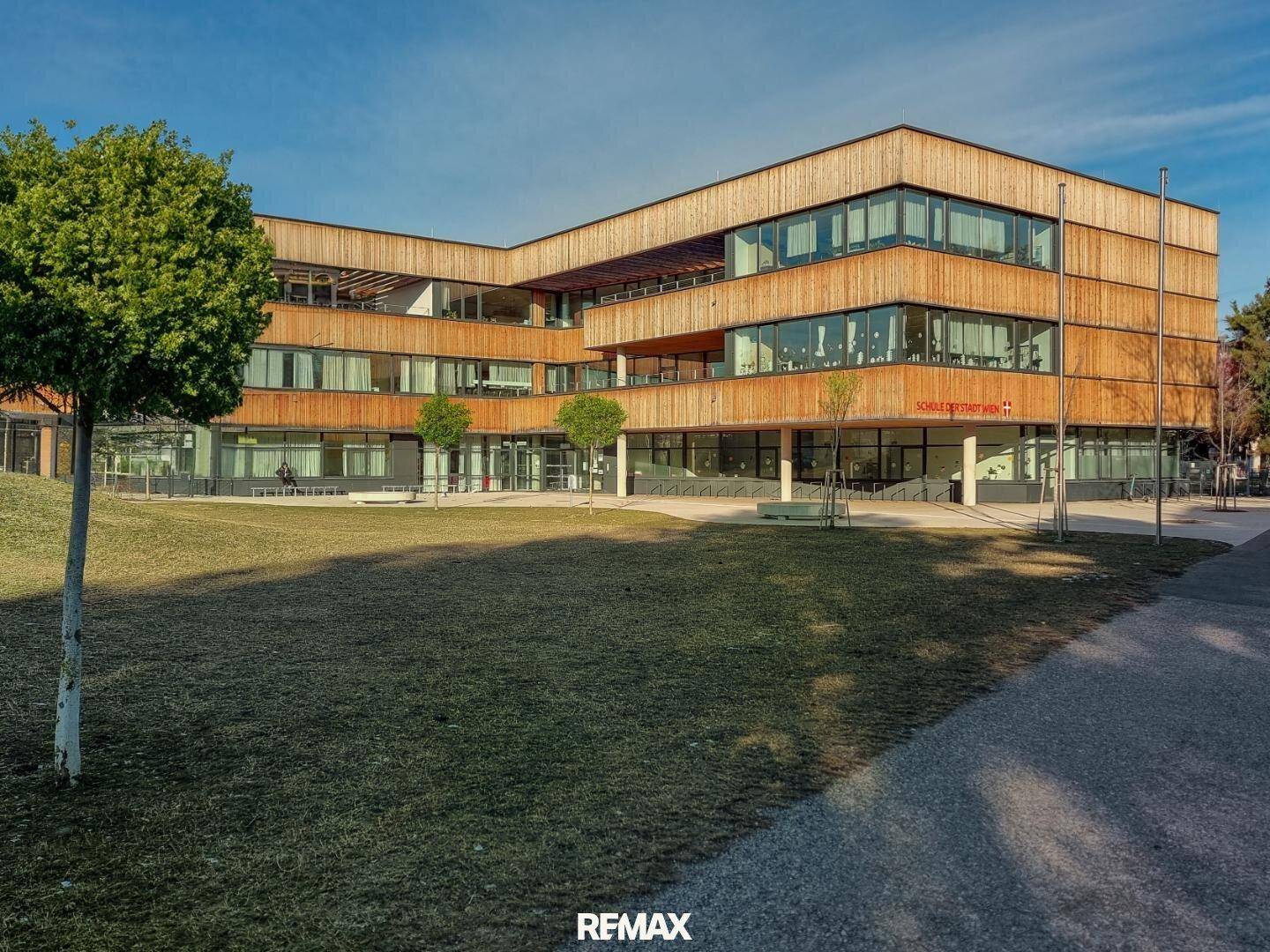 Moderne Architektur eines Schulgebäudes mit Holzfassade und großen Fensterfronten.