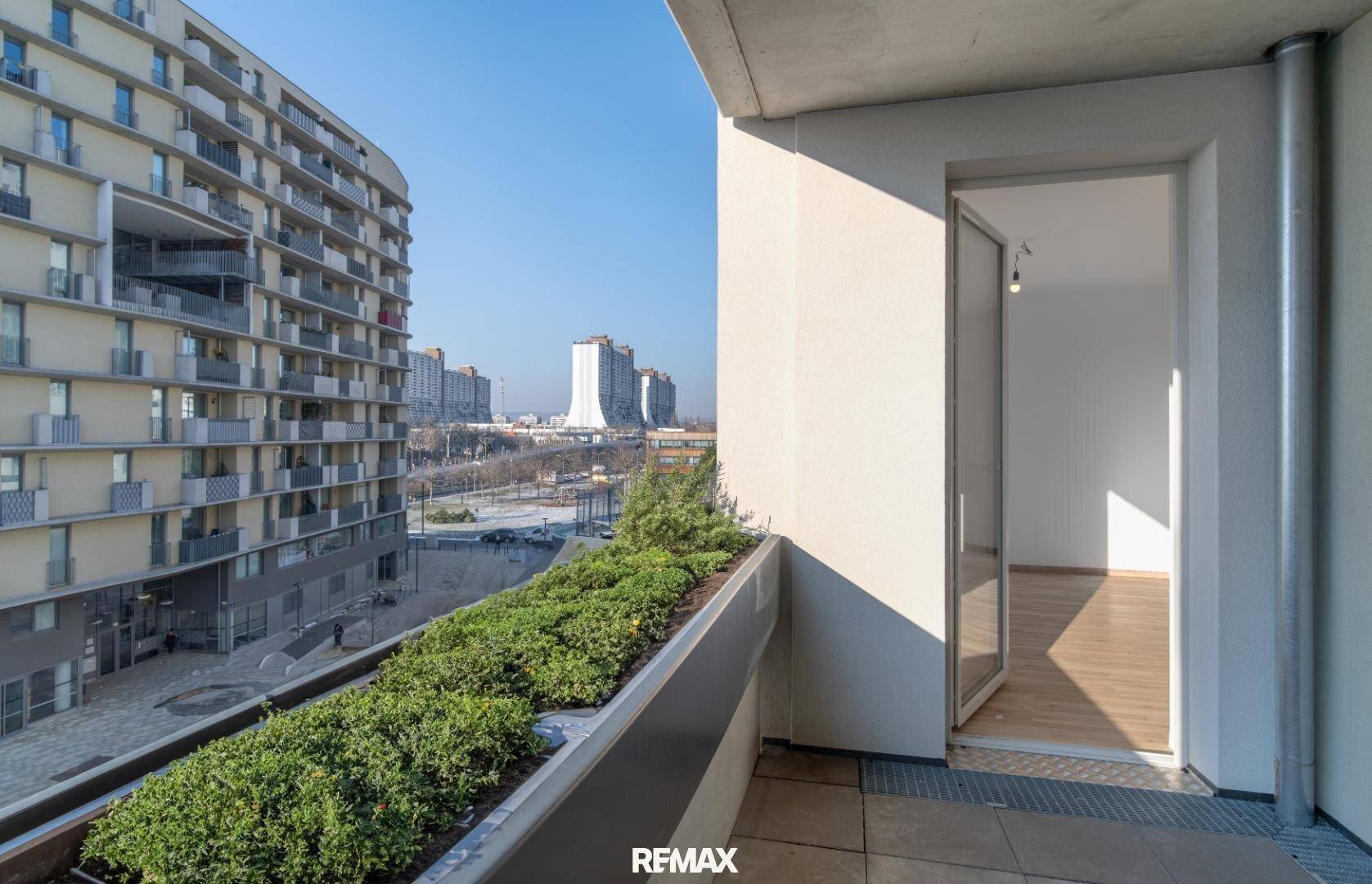 Balkon mit Pflanzen und Blick auf die umliegenden modernen Gebäude der Stadt.