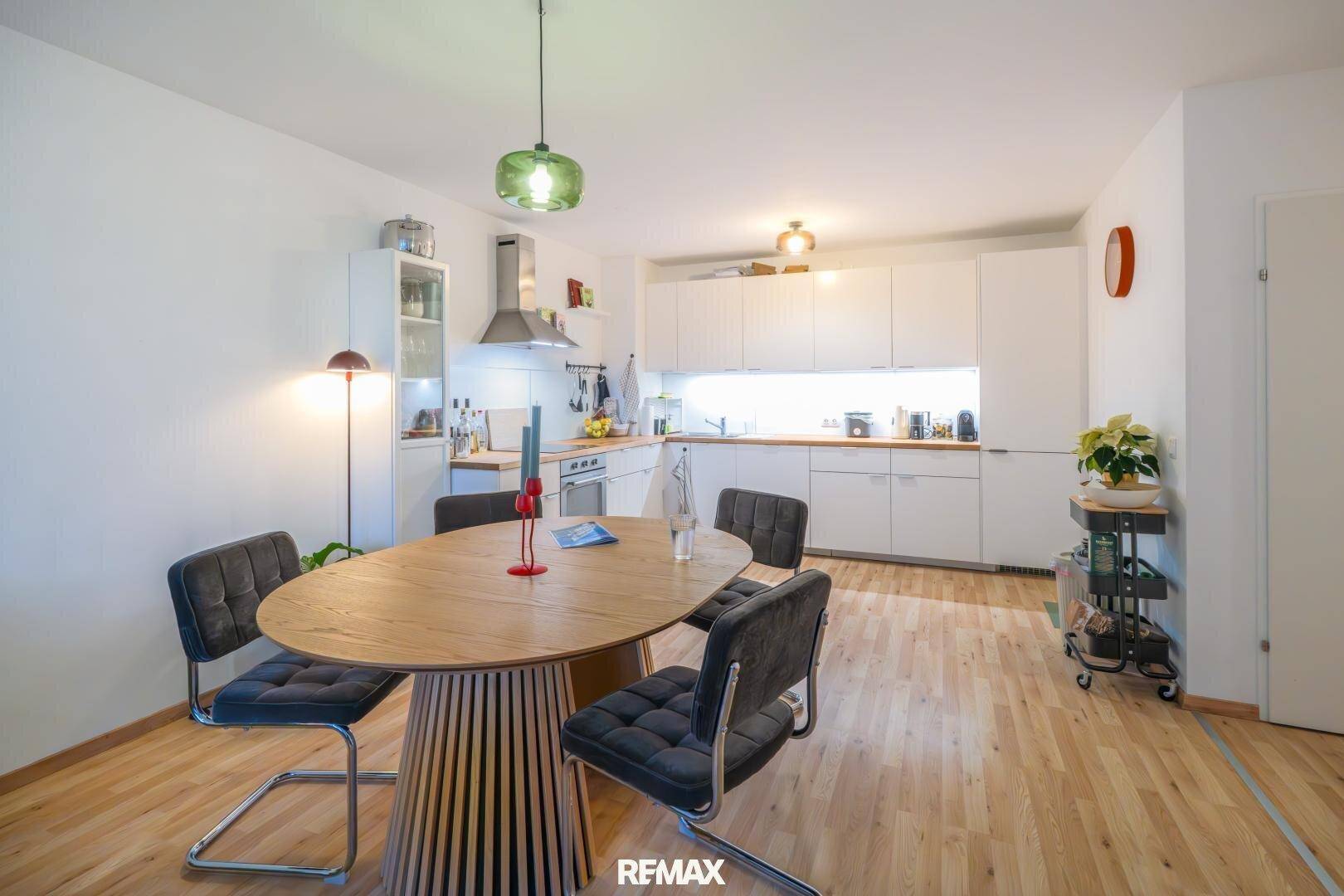 Offene Küche mit Essbereich, Holzboden und modernen weißen Schränken.