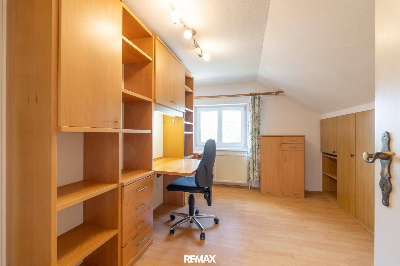Helles Arbeitszimmer mit Holzregalen, Schreibtisch und Dachschräge, ideal für Home-Office.