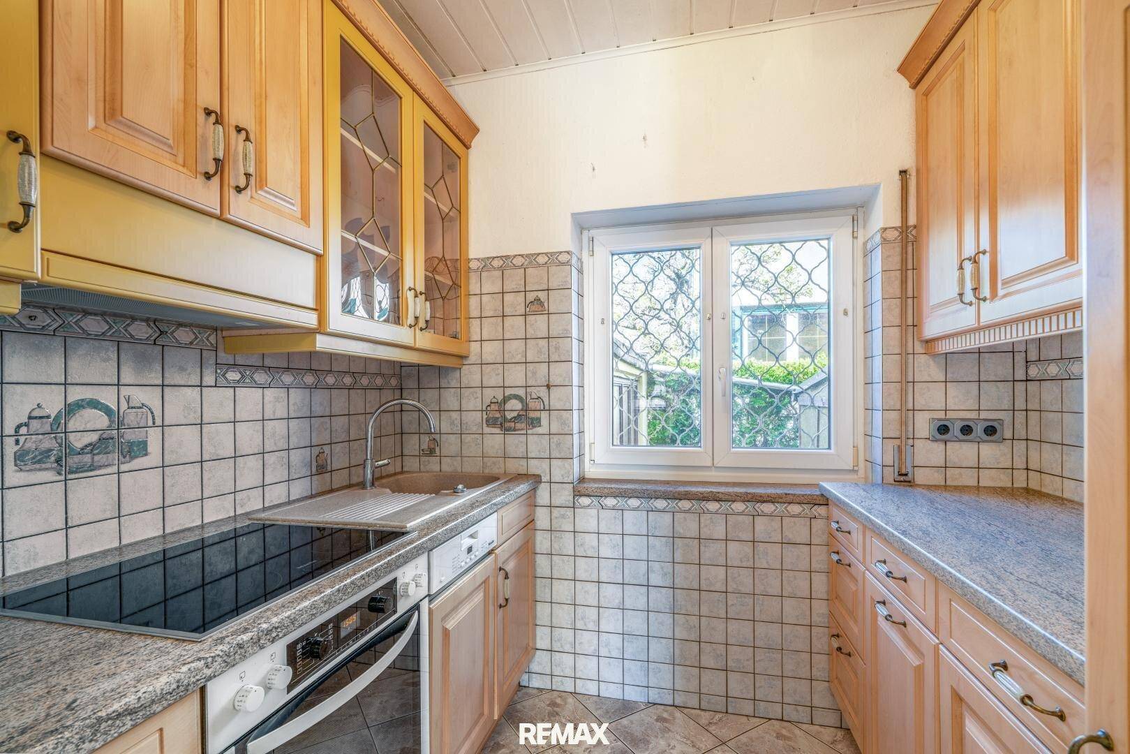 Traditionelle Küche mit Holzschränken, Granitarbeitsplatte und einem Fenster mit Blick ins Grüne.
