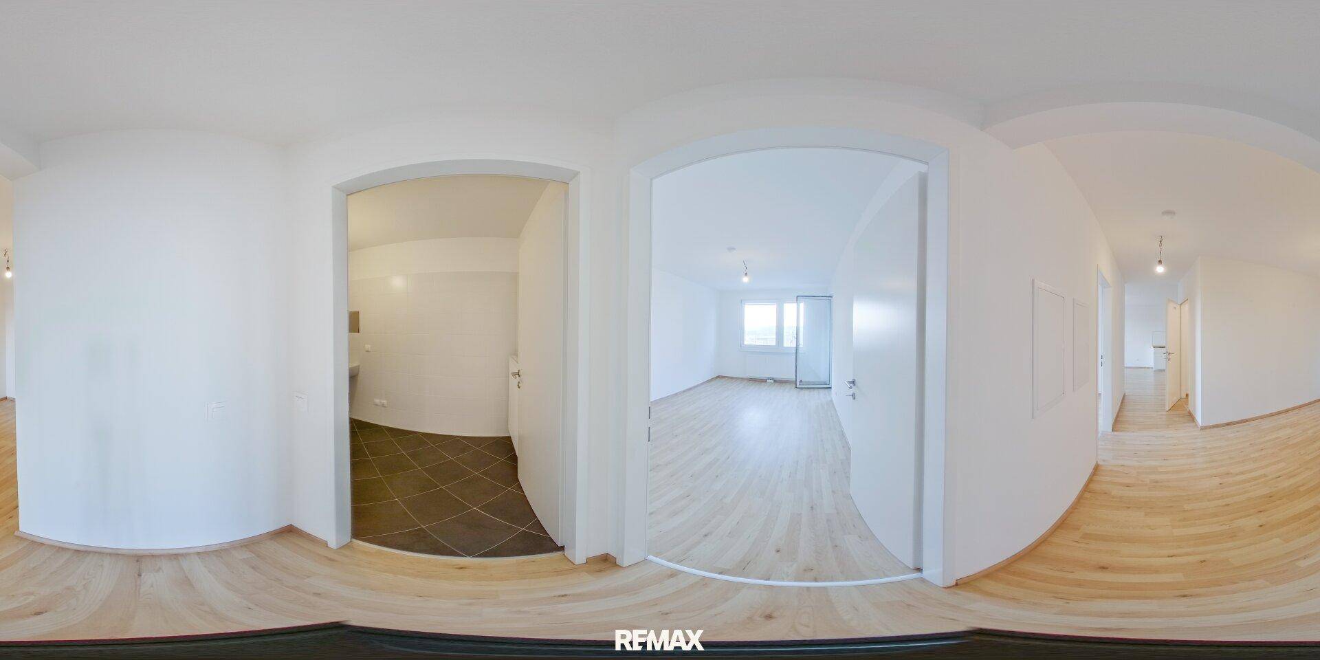Heller Flur mit Holzboden und Zugang zu verschiedenen Zimmern der Wohnung.