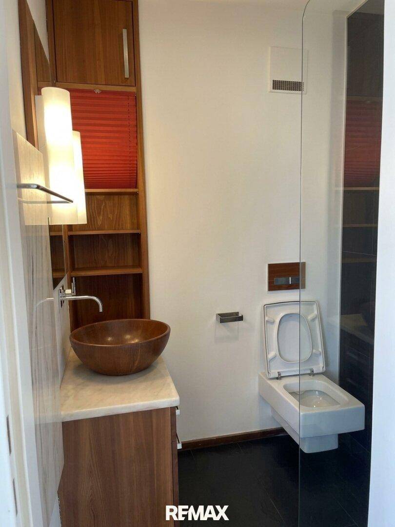 Modernes Gäste-WC mit Holzwaschtisch, Aufsatzwaschbecken und wandhängendem WC.