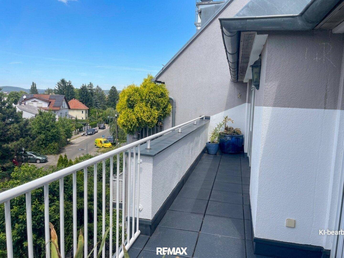 Langer Balkon mit weißem Geländer und weitem Blick über die umliegende Wohngegend.