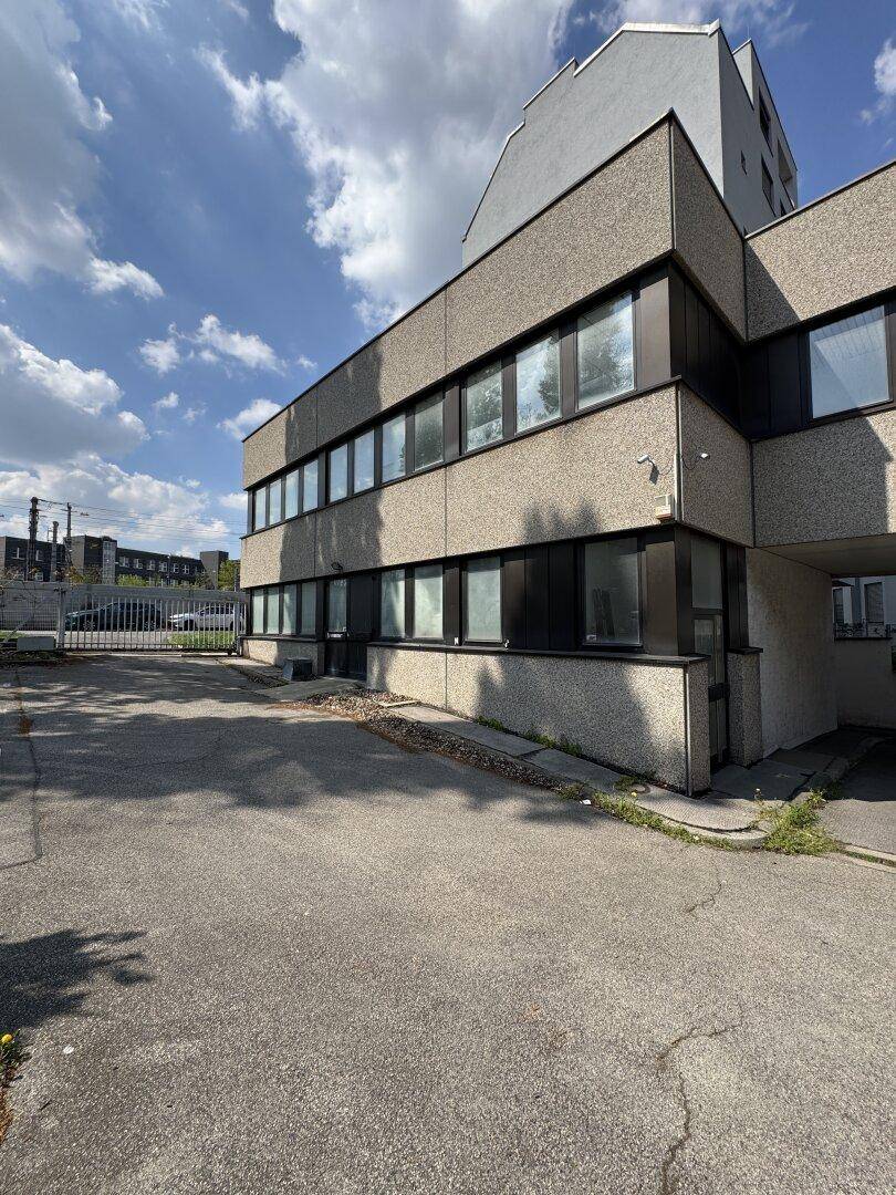 Detailansicht der Gebäudefassade mit strukturiertem Beton und einem asphaltierten Parkplatz.