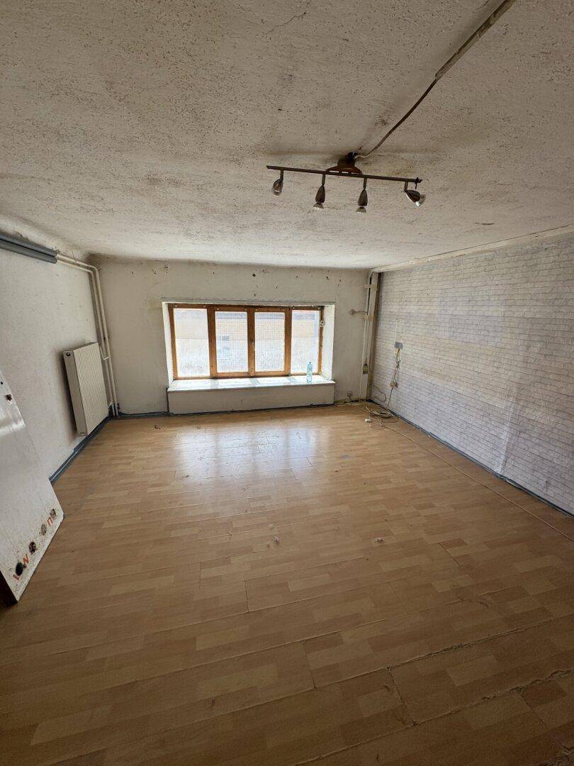 Leeres Zimmer mit Laminatboden, Fenster und Heizkörper, bereit zur individuellen Gestaltung.