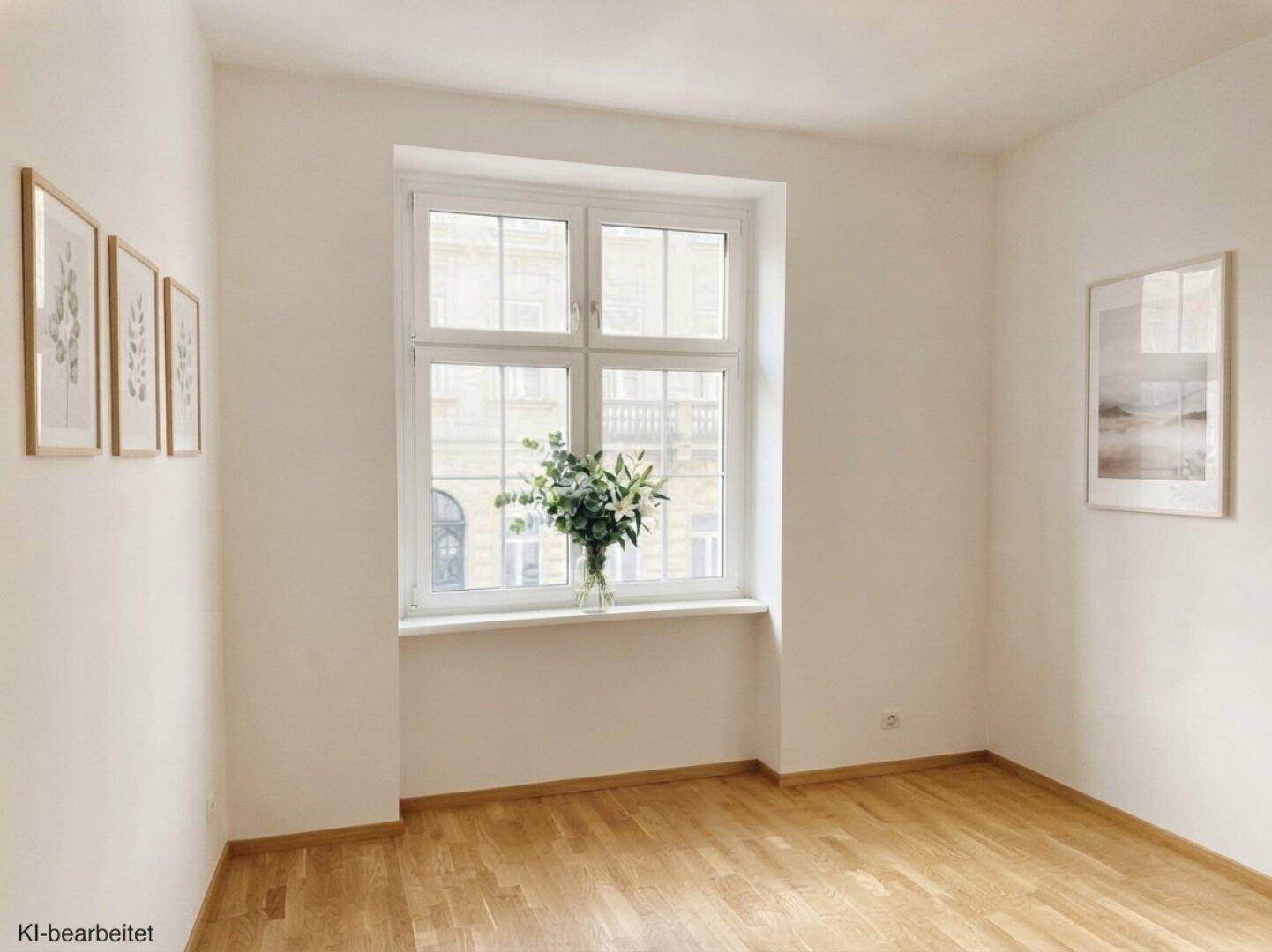 Heller, leerer Raum mit Holzboden und einem großen Fenster, das viel Tageslicht hereinlässt.