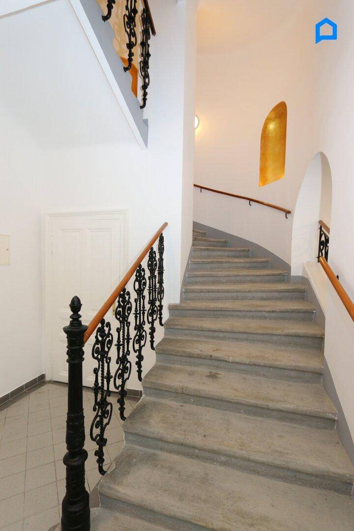 Historisches Treppenhaus mit Steinstufen und kunstvollen schmiedeeisernen Geländern in einem Altbau.