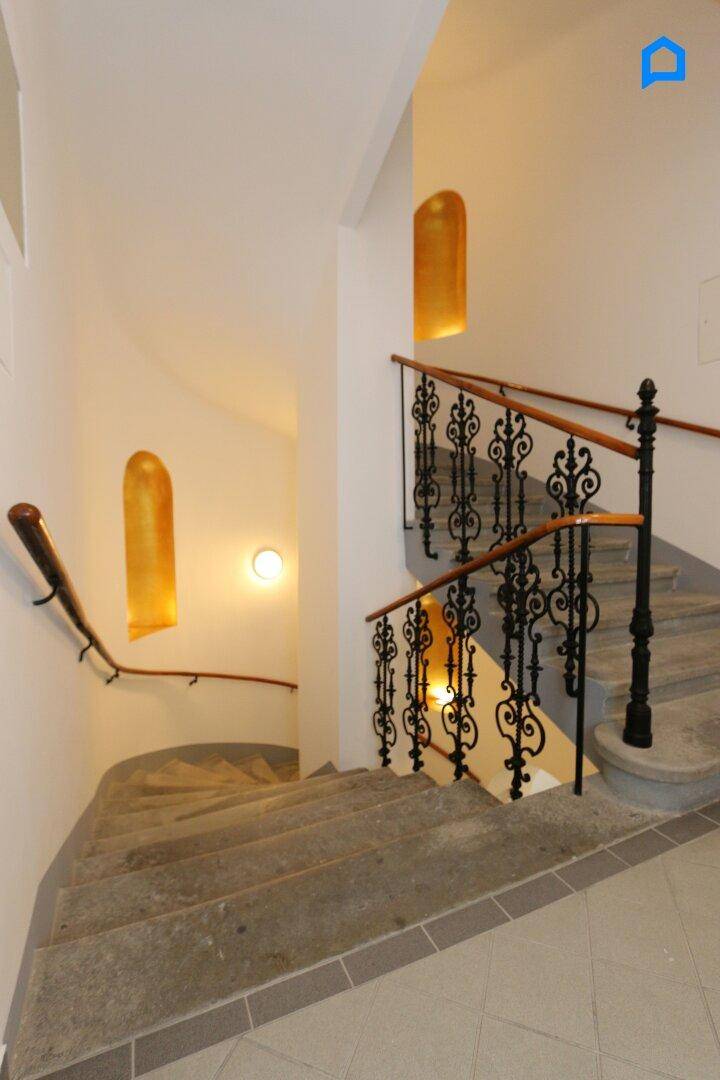 Historisches Treppenhaus mit Steinstufen und kunstvollen schmiedeeisernen Geländern in einem Altbau.