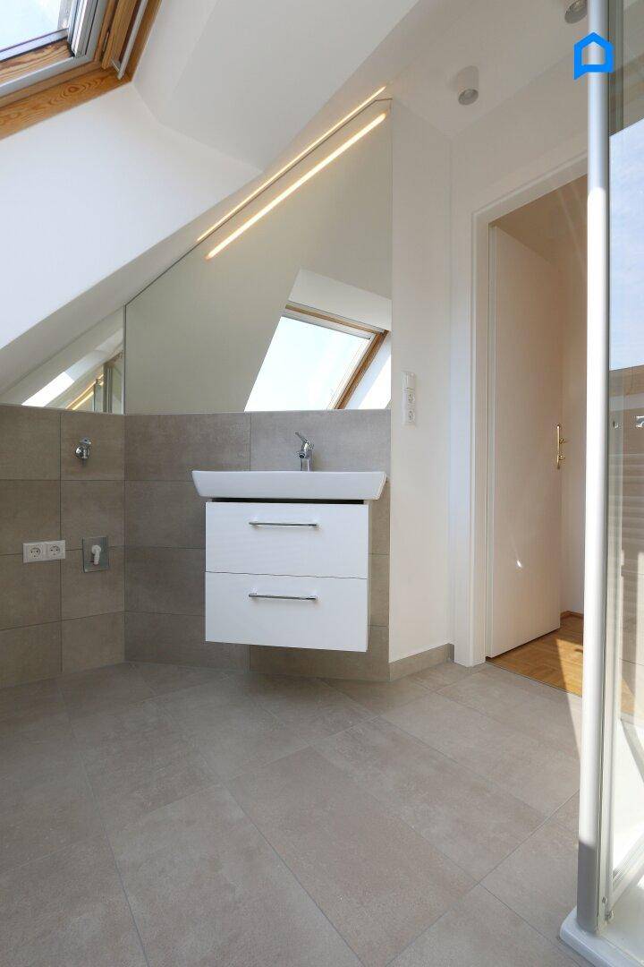 Modernes Badezimmer mit schwebendem Waschtisch, großem Spiegel und Duschkabine im Dachgeschoss.
