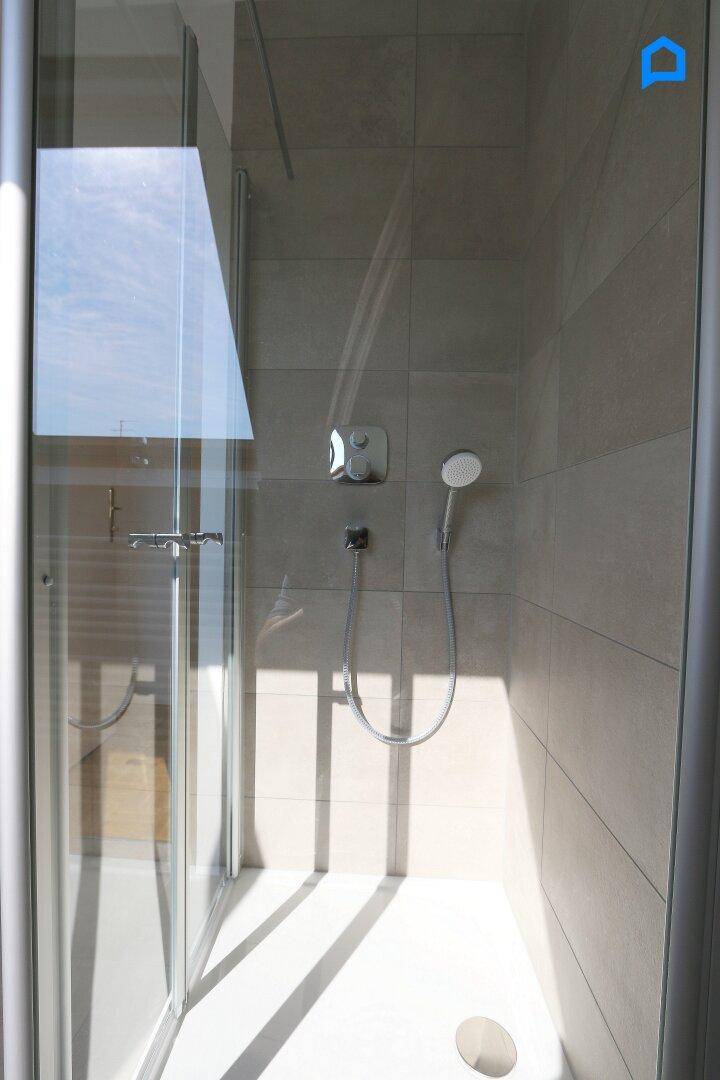 Moderne Duschkabine mit Glaswänden und Duscharmatur in einem hellen Badezimmer.