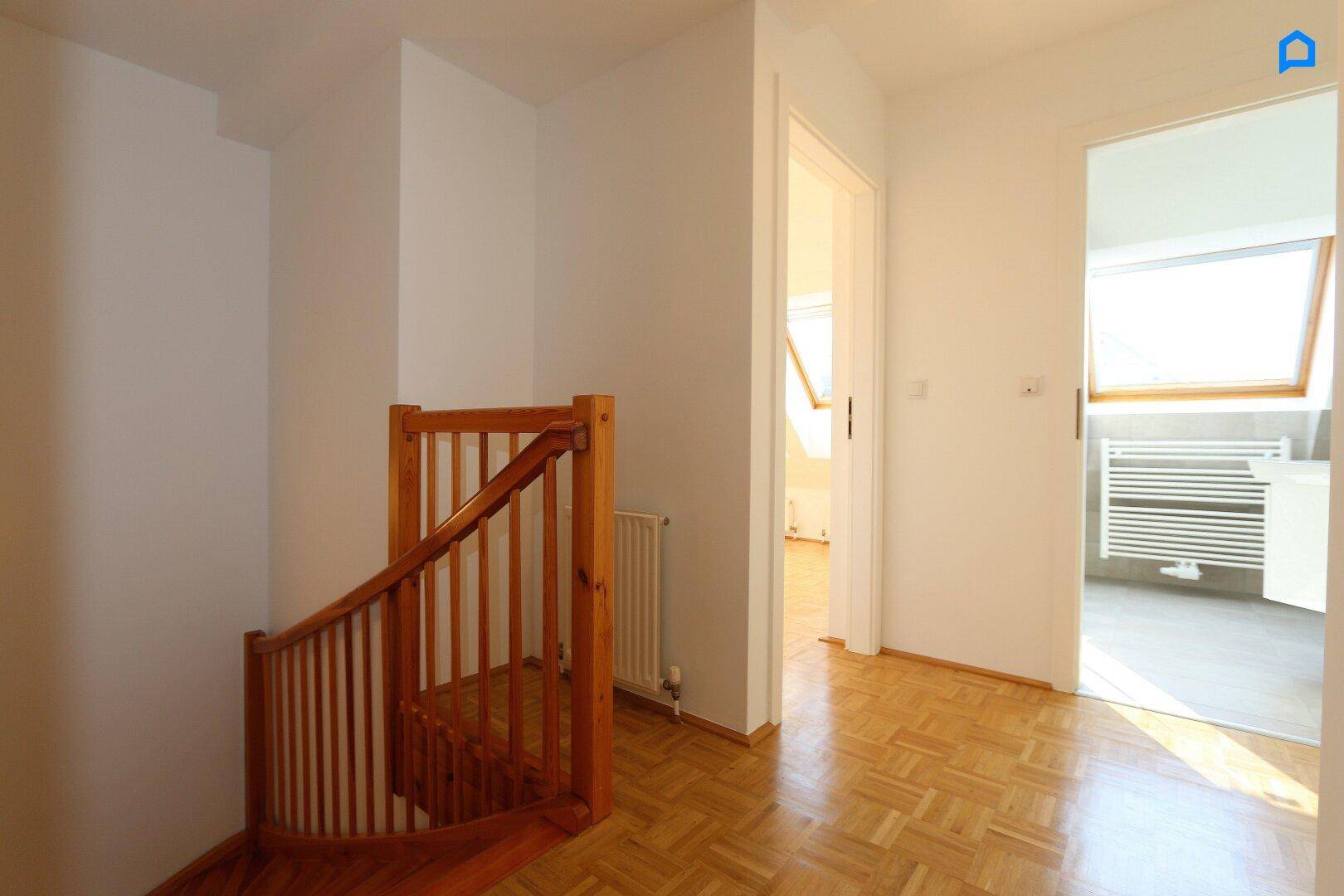 Heller Flur mit Parkettboden und Zugang zu verschiedenen Räumen, inklusive Badezimmer.
