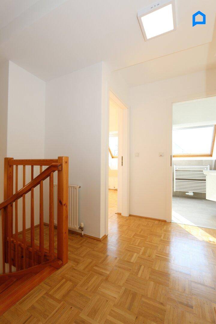 Heller Flur mit Parkettboden und Zugang zu verschiedenen Räumen, inklusive Badezimmer.