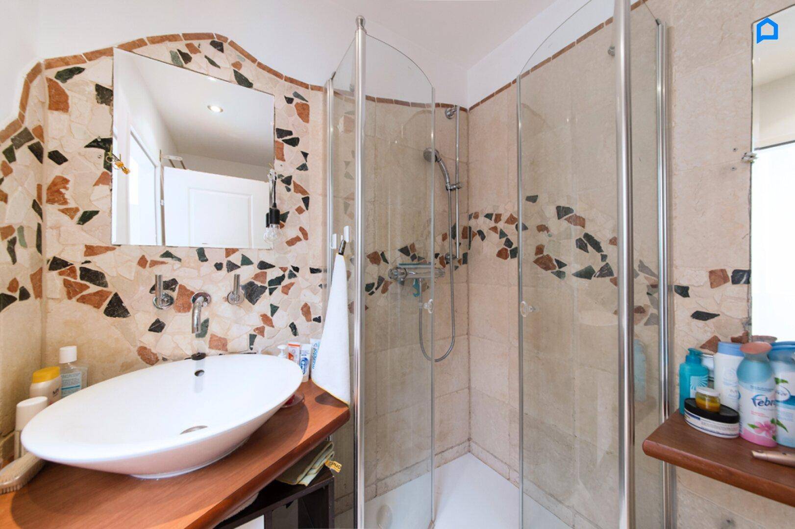 Badezimmer mit begehbarer Dusche, Aufsatzwaschbecken und dekorativen Fliesen.
